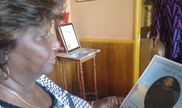 Carnela Hall looks at a picture of her nephew, Carnell Snell Jr., on the cover of his memorial service program. Snell was killed by Los Angeles police Oct. 1 while running away from a traffic stop. (Photo by Tami DeVine)